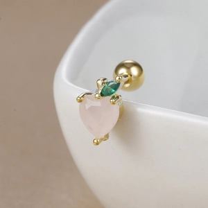 Close-up of peach-shaped 18K gold earring with pink heart gemstone and green leaf detail