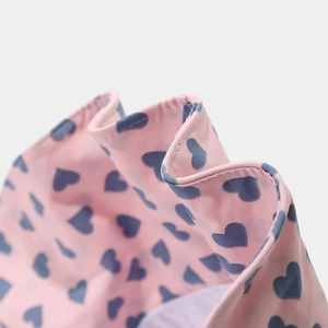 Macro detail of pink sun hat fabric with blue heart patterns and fine stitching work