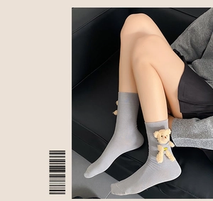 Detail of grey cotton knit crew socks featuring a cute 3D plush bear ornament accessory