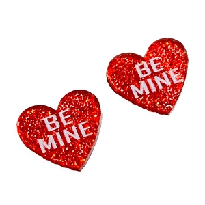 Gros plan de boucles d'oreilles cœur rouge pailleté avec texte Be Mine pour la Saint-Valentin