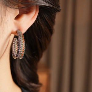 Detailed view of C-shaped hoop earrings featuring colorful cubic zirconia on a model