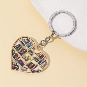 Artistic heart-shaped keychain with colorful bookshelf design on textured background