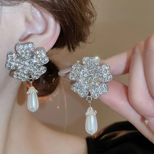 Detail showing crystal flower earrings with teardrop pearl pendants on a model