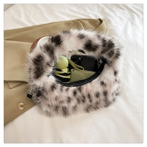 Spacious interior of plush faux fur crescent bag holding a folding umbrella and phone