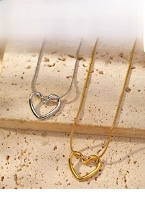 Detailed view of minimalist hollow heart pendants in gold and silver with snake chain
