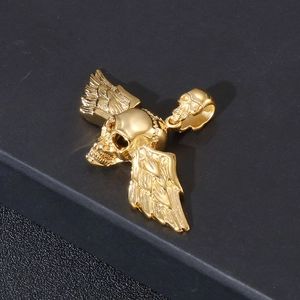 Gros plan détaillé d'un pendentif crâne doré en acier titane avec des ailes d'ange