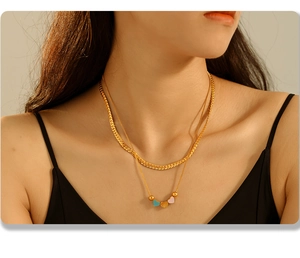 Close-up of golden double-layer necklace featuring colorful heart pendants and snake chain