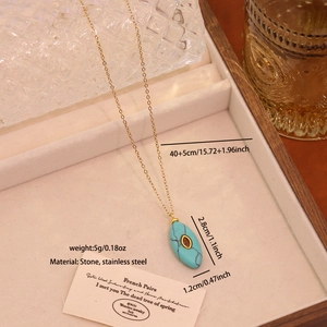Vue détaillée du pendentif ovale en turquoise avec chaîne en acier doré et dimensions