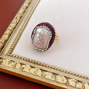 Macro shot of vintage gold-plated ring with baroque pearl and red gemstones