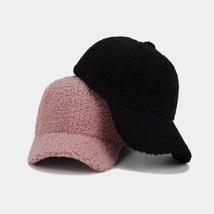 Close-up of pink and black fuzzy fleece baseball caps showing thick warm sherpa texture