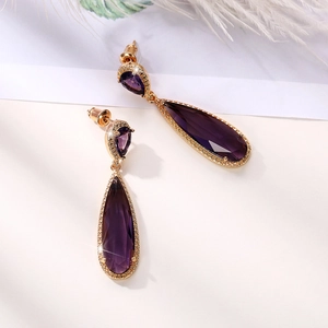 Close-up of deep purple teardrop zircon earrings with golden plating and halo stones