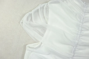 Close-up of white dress showing elegant mesh stitching and pleated shoulder detail