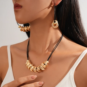 Detailed view of layered golden circular pendants and black cord on a fashion necklace