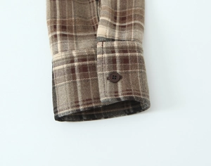Détail macro d'une chemise en flanelle à carreaux avec bouton marron et texture brossée