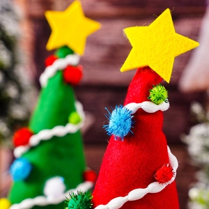 Close-up of red and green felt Christmas gnome hats with yellow stars and colorful pom-poms