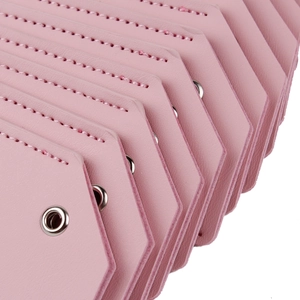 Close-up of pink PU leather luggage tags with fine stitching and metal grommet detail