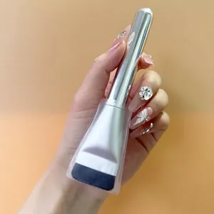 Flat top foundation brush with silver metallic handle and protective cover on hand