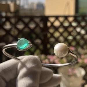 Silver open bangle featuring green triangle gemstone and white pearl decoration