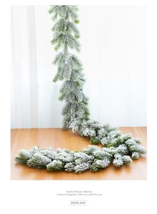 Close-up of artificial PE Christmas garland with realistic snow effect on wooden table