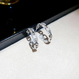 Macro shot of silver-tone link earrings with shimmering pavé zircon stones and a modern design