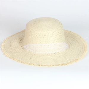 Detail of beige straw hat featuring white lace trim and fringe edges for summer beach wear