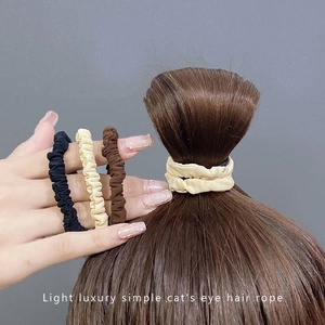 Set of three elastic scrunchies in black, beige and brown colors on model hair