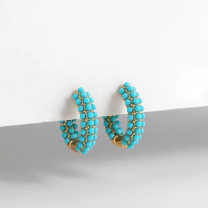 Detail of C-shaped hoop earrings featuring turquoise beads and 18K gold finish