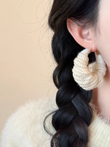 Vue détaillée de grandes créoles en laine tricotée crème portées pour un style hiver