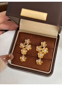 Macro detail of gold flower drop earrings with sparkling zircon stones in a velvet box