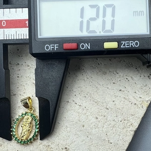 Detail shot of a 12mm gold Jesus pendant with green stones measured by digital calipers