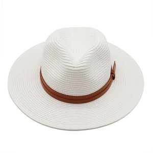 Détail d'un chapeau de paille blanc avec ruban en cuir marron et boucle métallique latérale