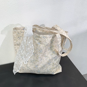 Detailed close-up of floral canvas tote bag featuring blue flowers and white lace ribbon bow