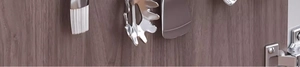 Close-up of stainless steel kitchen utensils on sliding track hooks with dark wood background