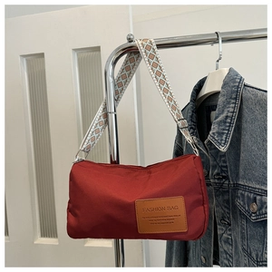 Detail of red nylon crossbody bag with stylish geometric wide strap and brown label