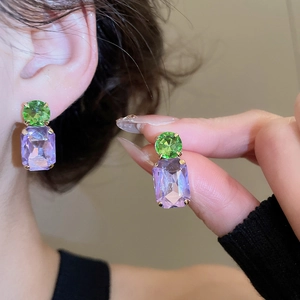 Detail of green and purple geometric crystal earrings with gold claw settings