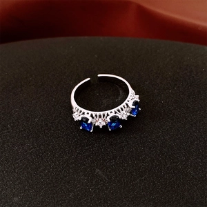 Gros plan détaillé d'une bague ouverte avec zircons bleus sur texture noire mate