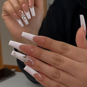 Macro shot of long coffin French nails with nude base, white tips and silver butterfly charms