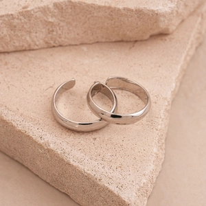 Macro view of two polished silver minimalist open rings on textured stone display