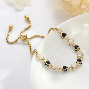 Adjustable golden bracelet with heart enamel charms on a minimalist white ceramic plate