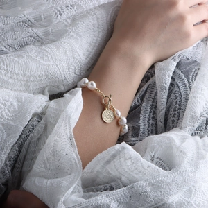 Dettaglio del bracciale con perle d'acqua dolce barocche, ciondolo a moneta d'oro e chiusura OT