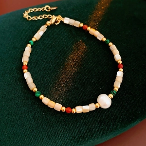 Vue détaillée du bracelet doré avec perle baroque et perles de coquillage sur velours vert