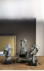 Detail of three Nordic abstract thinker sculptures in vintage silver resin on wooden table