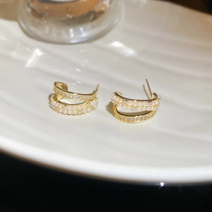 Dettaglio macro di orecchini placcati oro 14k con eleganti perle bianche e zirconi brillanti