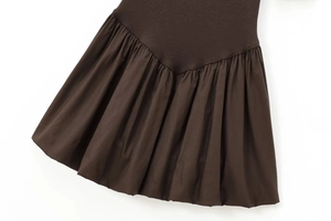 Detail of mock neck dress showing ribbed knit texture and brown pleated woven fabric seam