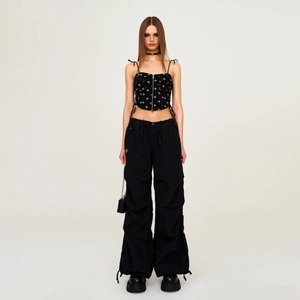 Full-body studio shot of a black cotton camisole with cross embroidery and cargo pants