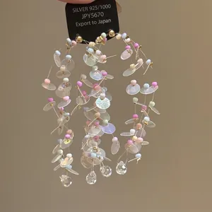 Close-up of long tassel earrings with colorful beads, sequins and teardrop crystals