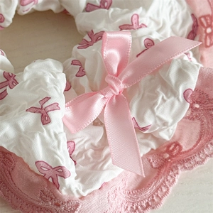 Macro detail of white pleated lace hair scrunchie with pink ribbon bow and lace trim