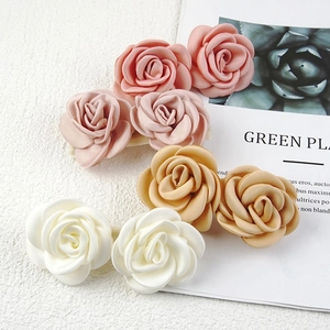Close-up of three handmade fabric rose hair ties in pink, nude and white colors