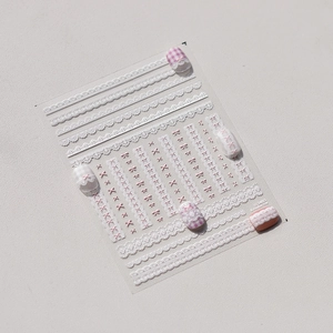 Detail of embossed nail stickers featuring white lace ribbons and pink bow-knot patterns
