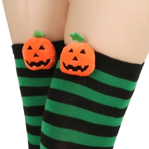Detail of Halloween over-knee socks with green stripes and a plush pumpkin accent